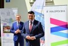 Dwóch uśmiechniętych mężczyzn stojących przed budynkiem.