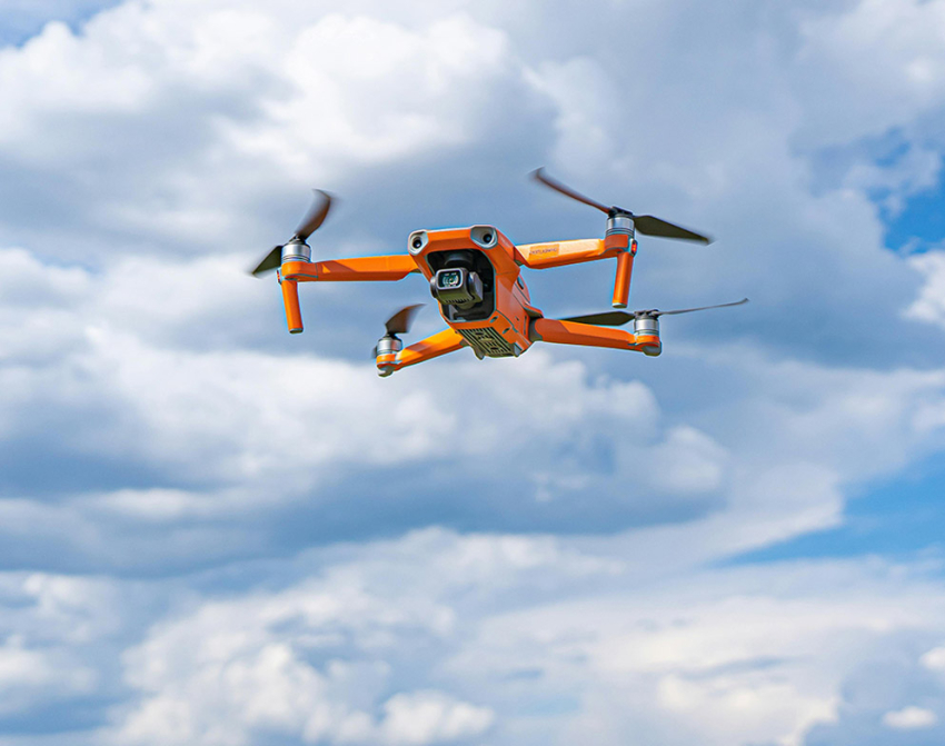 Pomarańczowy dron z kamerą w czasie lotu