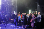Kulisy teatru. Kobieta pokazuje grupie osób sprzęty się tam znajdujące.