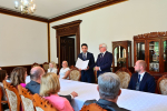 Grupa osób przy stole konferencyjnym, w eleganckiej sali.