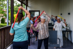 Seniorzy ćwiczą z trenerem na tarasie.