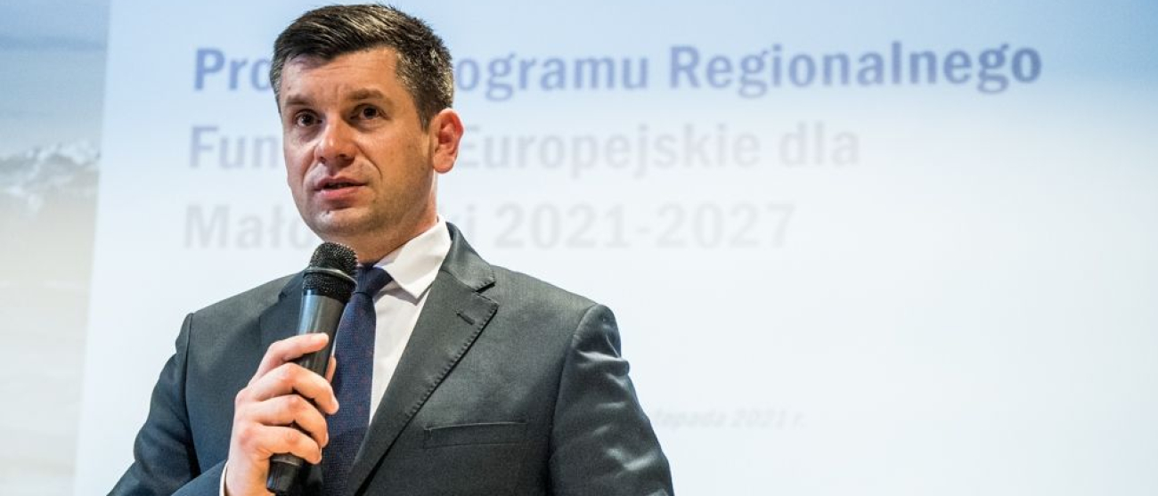 Wicemarszałek Łukasz Smółka trzyma w ręce mikrofon i przemawia.