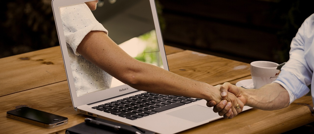 Laptop i ręce w uścisku gratulacji.