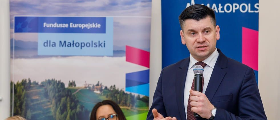 Wicemarszałek Łukasz Smółka trzyma w ręce mikrofon i przemawia.